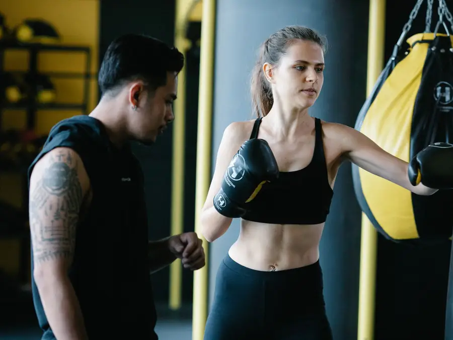 Coach con i colpitori mentre un'atleta tira un diretto durante una sessione di boxe